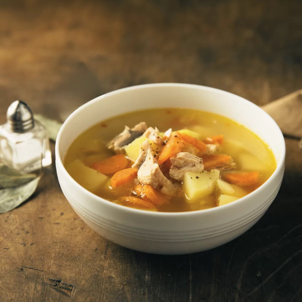 Warm, AIP-compliant bowl of soup on a wooden table, nourishing and comforting for winter health.