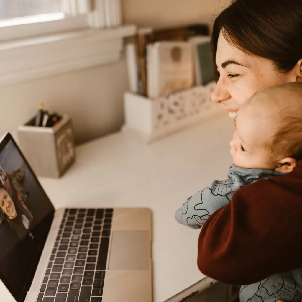 Mother and baby smiling during a video call on a computer screen, embracing connection during the winter season.